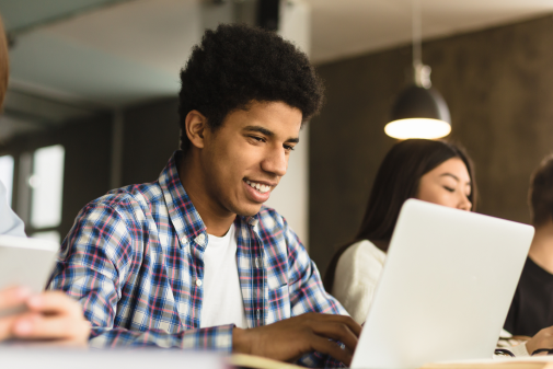 Male student smiling at laptop